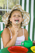 Little girl in big hat eats sweets and drinks tea
