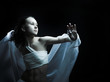 Girl in white raiment dancing in semidarkness