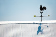 Rooser Weather Vane Atop Tin Roof in Clear Blue Sky Rooser Weather Vane Atop Tin Roof in Clear Blue Sky