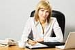 Photo: Young beautiful business lady at desk writing. Young beautiful business lady at desk writing.