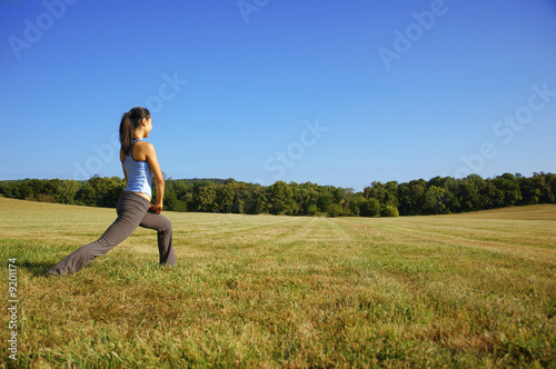Photo: Girl practicing yoga in a summer meadow. Girl practicing yoga in a summer meadow.