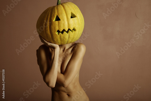 Photo: Sexy lady with big pumpkin on head. Surrealstic portrait. Sexy lady with big pumpkin on head. Surrealstic portrait.