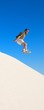 An image of a man jumping off of sand dunes An image of a man jumping off of sand dunes