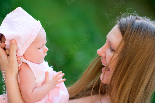 Photo: Happy young mother and her baby girl outdoors at sunny day Happy young mother and her baby girl outdoors at sunny day