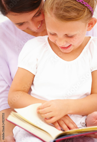 Happy young mother with her daughter reading a book
