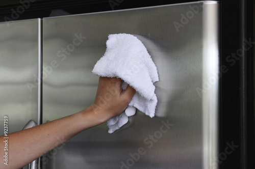 Photo: Woman's hand polishing stainless stell fridge Woman's hand polishing stainless stell fridge