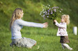 Daughter giving mother bunch of flowers, side view