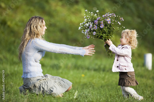 Photo: Daughter giving mother bunch of flowers, side view Daughter giving mother bunch of flowers, side view