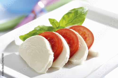 Photo: Mozzarella cheese with tomatoes and basil, close-up Mozzarella cheese with tomatoes and basil, close-up