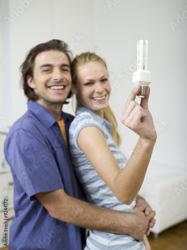 Photo: Couple embracing, woman holding bulb Couple embracing, woman holding bulb