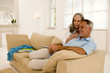Mature couple sitting on sofa, watching TV, side view Mature couple sitting on sofa, watching TV, side view