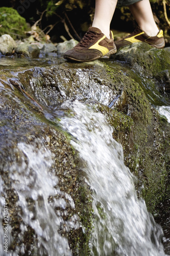 Photo: Young woman crossing stream, low section Young woman crossing stream, low section