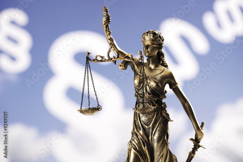 Photo: Justitia figurine in front of paragraphes Justitia figurine in front of paragraphes