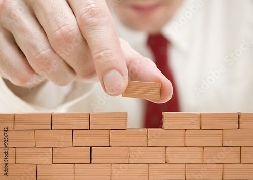 Foto: hombre de negocios construyendo un muro hombre de negocios construyendo un muro