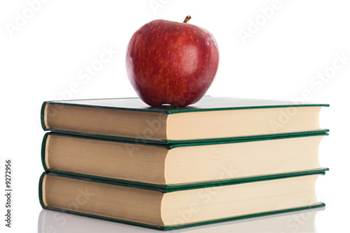 Photo: A red apple on top of three books on a white background A red apple on top of three books on a white background