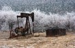 Old, rusty oil well on a winter landscape