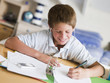 Young Boy Doing His Homework While Listening To Music On MP3