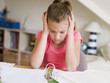 Young Girl Doing Her Homework With Her Head In Her Hands