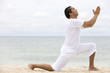 Beach man doing yoga exercises in a tranquil location