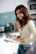 A young woman reading a cookery book in the kitchen