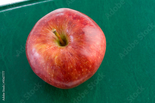 Photo: Apple red on a green book seen from above Apple red on a green book seen from above