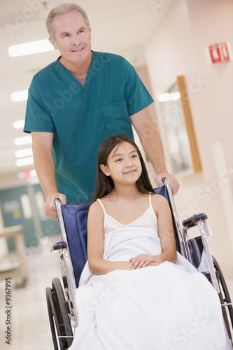 Photo: An Orderly Pushing A Little Girl In A Wheelchair An Orderly Pushing A Little Girl In A Wheelchair