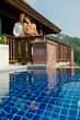 Young attractive couple standing by their pool villa with drinks