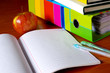 Colorful student gear, blank notebook and a red apple