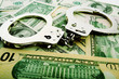 Silver handcuff and dollar bank notes