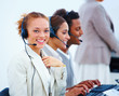 Closeup of happy young operators sitting with headsets