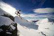 Snowboarder riding off cliff with deep blue sky in background