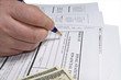 Hand filling income tax form with pen