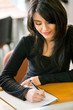 Beautiful girl studying in the library - smiling and writting