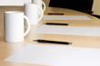 cups pencils and white paper in a meeting room