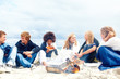 Young friends sitting by fire and eating pizza on the beach