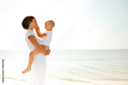 Photo: young woman holding a young boy on a beach young woman holding a young boy on a beach