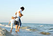 woman and two young boys holding hands and jumping on a beach