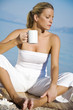 young female drinking her morning herbal tea on the beach