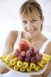 Foto: female holding a plate full of fresh fruit female holding a plate full of fresh fruit
