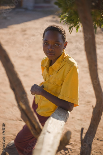 Foto: african boy with yellow shirt sitting in the shade african boy with yellow shirt sitting in the shade
