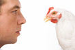Profiles of man and white chicken looking at each other