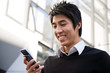 A casual asian businessman texting on his cell phone