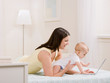 Foto: Side view of mother and baby playing with laptop on bed Side view of mother and baby playing with laptop on bed