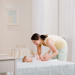 Foto: Loving mother changing babyÕs diaper on bed Loving mother changing babyÕs diaper on bed