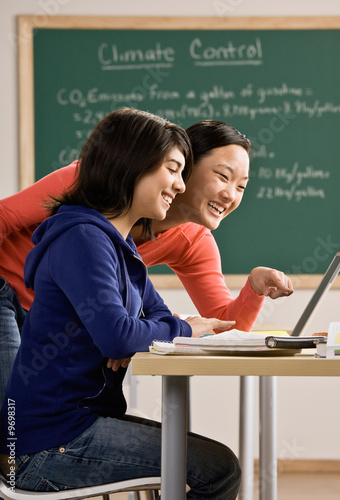 Photo: Student with laptop doing homework with friend in classroom Student with laptop doing homework with friend in classroom