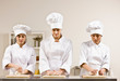 Photo : Chef co-workers in toques kneading dough in commercial kitchen Chef co-workers in toques kneading dough in commercial kitchen