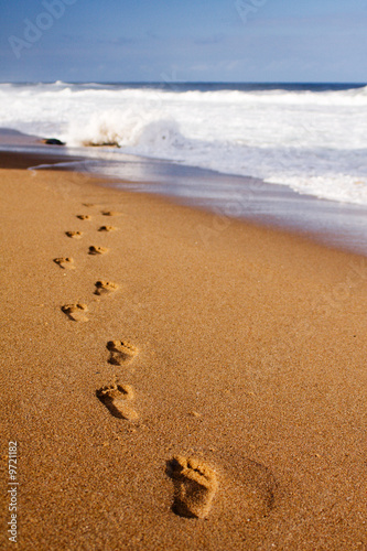 Photo: Footprints on the beach sand leading away from the viewer Footprints on the beach sand leading away from the viewer