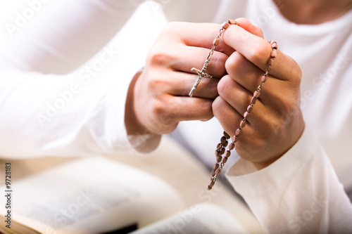 Photo: Christian believer praying to God with rosary in hand. Christian believer praying to God with rosary in hand.