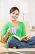 Woman relaxing on sofa in livingroom enjoying reading a book