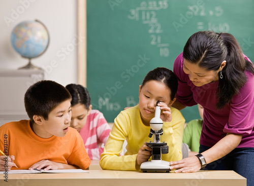 Photo: Student peering through microscope in science classroom Student peering through microscope in science classroom